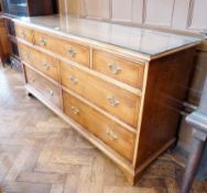 A reproduction yew wood veneer chest, with loose glass top, three frieze drawers, with four