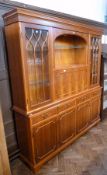 A modern reproduction yew wood veneer based cabinet with dentil cornice, central open shelf, with