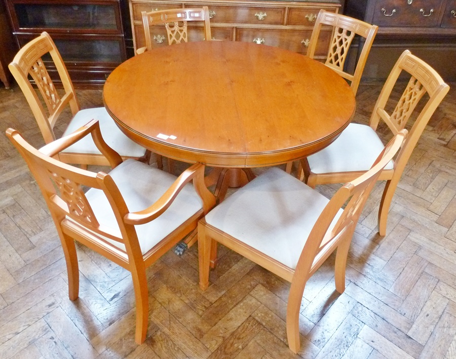A reproduction yew wood veneer circular-topped dining table, on pedestal support with outswept legs,