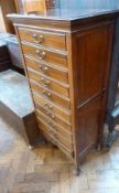 An early 20th century mahogany music chest of ten short drawers with hinged fronts, raised on bun