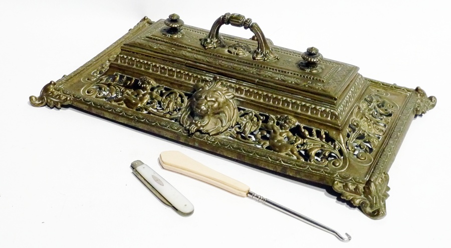 A brass inkstand, lidded central section, with two circular glass inkwells to interior, foliate