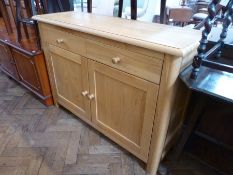 A modern pale oak cupboard with two frieze drawers, pair of cupboard doors below enclosing shelf,