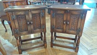 Pair reproduction carved oak bedside cupboards, each with foliate carved framed panel door on turned