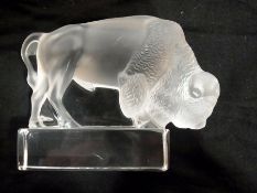 A Lalique opaque glass bison, raised on a rectangular plinth, length 12cm (af)
