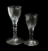 Two old English wine glasses with round funnel bowls, cut faceted stems, on a raised circular