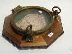 An old brass ship's porthole, mounted on an octagonal mount