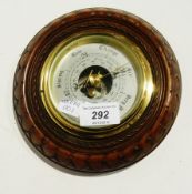 An aneroid barometer in a carved walnut case with silver dial, dia. 19cms