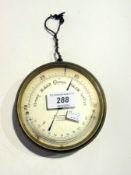 An aneroid barometer in a brass drum shaped case with silvered dial, and temperature gauge by