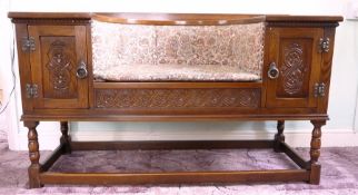 An oak reproduction hall seat with two small cupboards, carved panelled doors, guilloche-style
