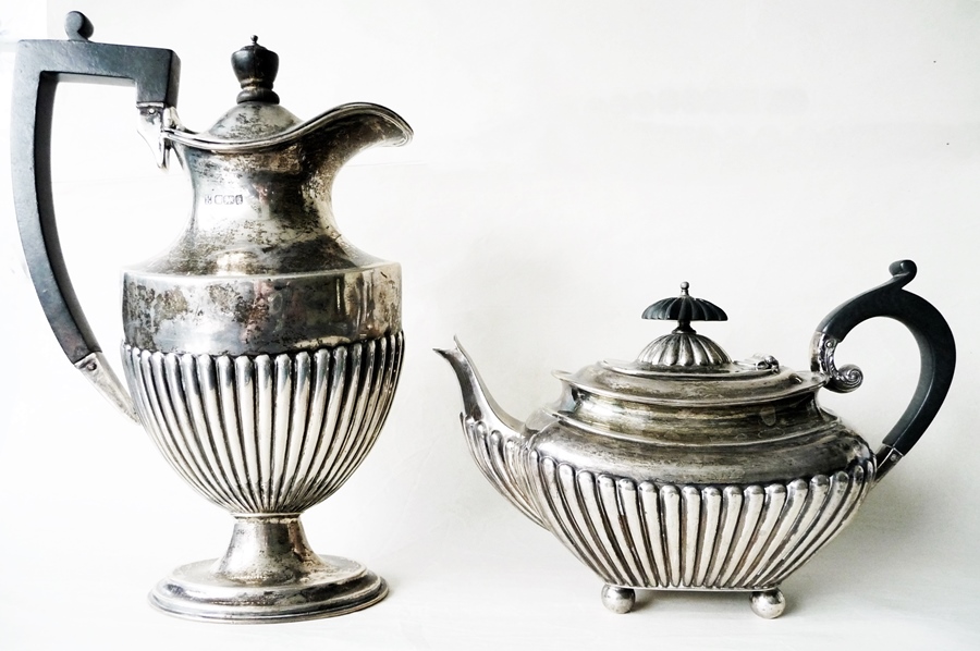 A silver half-ribbed hot water jug, Sheffield 1902 and a similar teapot (marks rubbed) (2)