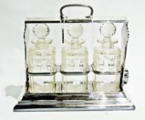 A silver plated tantalus, with three glass decanters, on stepped base, 33cm high