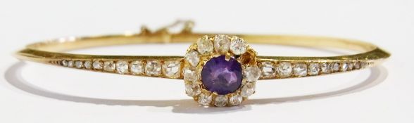 Late Victorian/Edwardian gold-coloured metal amethyst and diamond bangle, the circular amethyst
