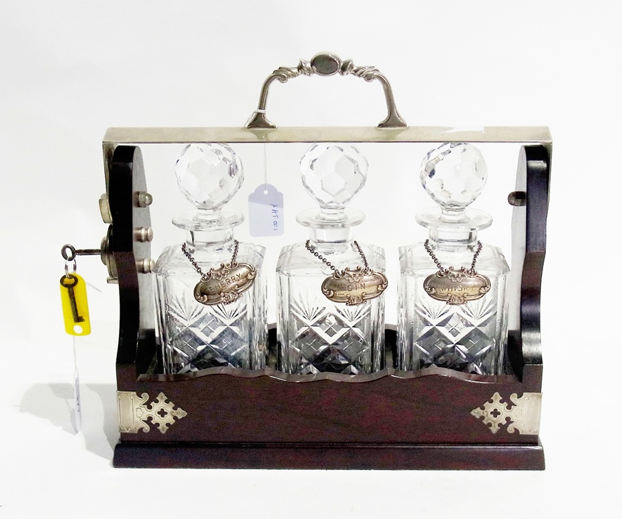 A wooden and silver plated tantalus with three glass decanters, and sherry, gin and whisky labels,