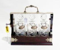 A wooden and silver plated tantalus with three glass decanters, and sherry, gin and whisky labels,