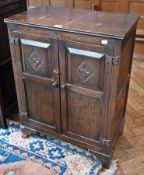 A modern oak cupboard, with pair carved panelled doors enclosing two shelves, on bracket feet,