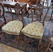 A pair of Victorian mahogany dining chairs, foliate carved and pierced back, upholstered stuffover