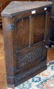 A modern oak hanging corner cupboard, panel door enclosing two shelves, with turned wood handles,