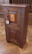 An oak cupboard, with pair panelled doors, one with handpainted plaque, enclosing shelving space, on