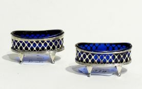 A pair of Edwardian silver oval open salts, with trelliswork design and blue glass liners, raised on