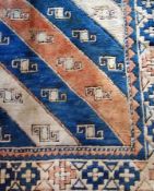 A Middle Eastern wool carpet, cream ground, blue and orange geometric border, with Caucasian style