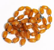 Carved amber bead double string necklace, of oval gadrooned shaped beads, and pair matching clip