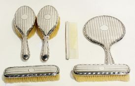 A six piece silver-backed dressing table set comprising:- pair hairbrushes, handmirror, pair