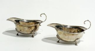 A pair of George V silver sauce boats, with reeded border, raised on pad feet, with scroll