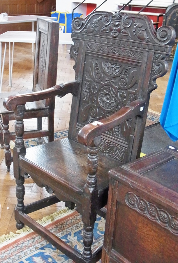 An antique oak carver, of Jacobean style, carved panelled back depicting mask and flowers