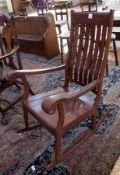 A modern stained wood rocking chair, with comb back and inlaid floral decoration, wooden seat on