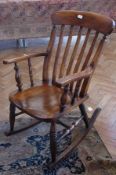 A stained wood rocking chair, comb back, wooden seat on turned supports