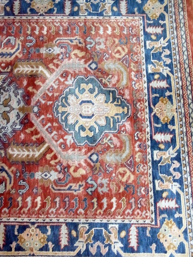 New Zealand wool rug, dark coral ground, blue border with central medallions in green and brown,