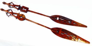 Two African hardwood spear-shaped paddles, with figures on handle and pierced decoration, 137cm long