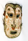 A Papua New Guinea mask with applied tusks and feathers, 91cm high approx.