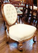 A Victorian walnut nursing chair, with oval carved and cream upholstered back, cream upholstered