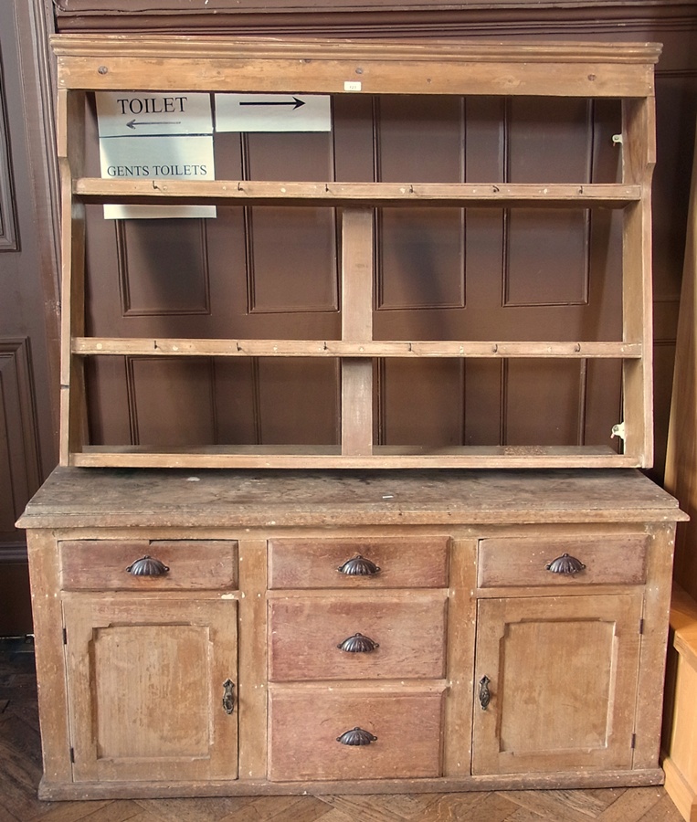 An antique pine dresser with two shelves above, an arrangement of drawers and cupboards below (
