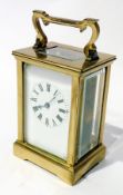 Brass carriage time piece with scrolled handle, bevelled glass panels on bracket feet, 15cm high