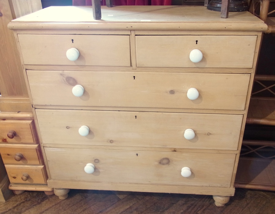 A pine chest of two short and three long drawers, with white circular handles, on bun feet, 103cm