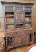 A 17th century style oak dresser, with carved top section, single frieze cupboard surrounded by