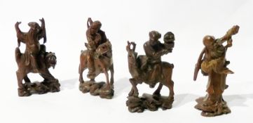 Set of four oriental carved hardwood figures, three of men riding animals and another of sage
