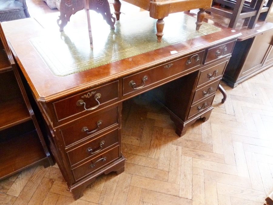 A Mahogany kneehole pedestal desk, with inset leather writing top, an arrangement of nine drawers