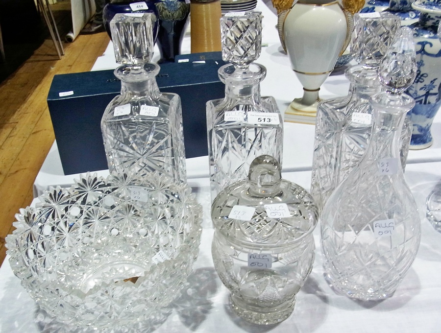 Three matching cut glass decanters, another glass decanter, a lidded jar and cover and a heavily