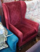 A 20th century wing armchair, maroon upholstery, on curved, carved supports