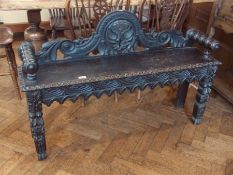 A Victorian ebonised carved oak window seat, with foliate carved back, on carved square legs,