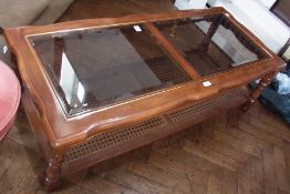 A modern rectangular coffee table, with bevelled glass panel top, on turned legs with cane panel