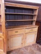 An old pine dresser with open two shelf rack, two frieze drawers with cupboards below enclosing