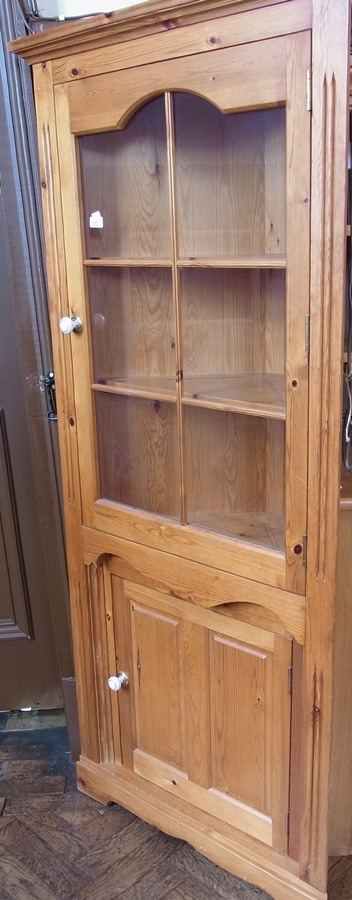 A modern pine glazed corner cupboard, three shelves in the upper section, panelled cupboard below