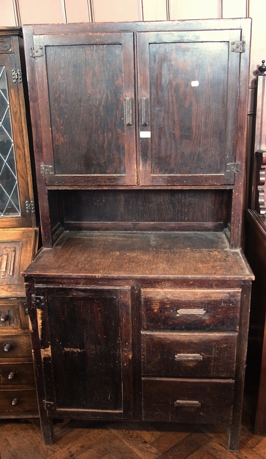 A twentieth century stained wood kitchen cabinet, the top with panelled doors enclosing shelves,