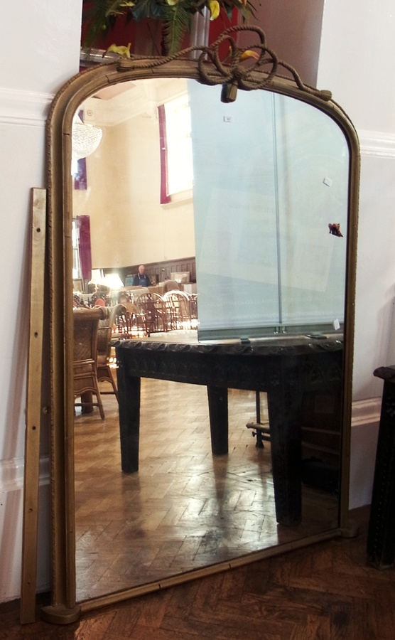 Large Victorian gold painted over-mantel mirror, the arched top with rope bow and tassel pediment,