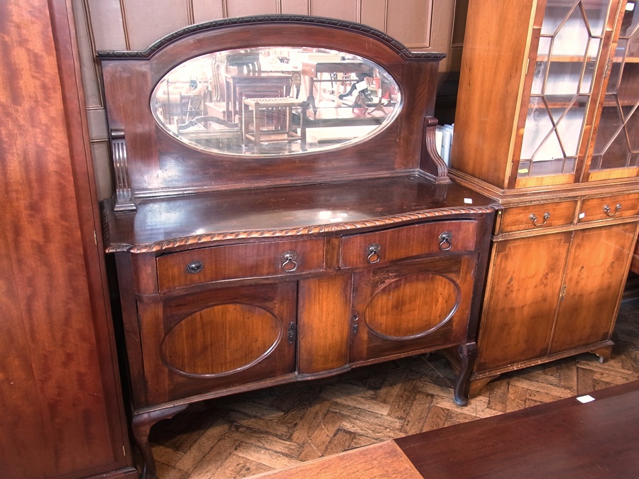 Twentieth century Chippendale style mahogany oval mirror back sideboard with serpentine front and