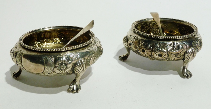 Pair of Victorian silver and parcel gilt circular salts with floral repousse decoration on paw